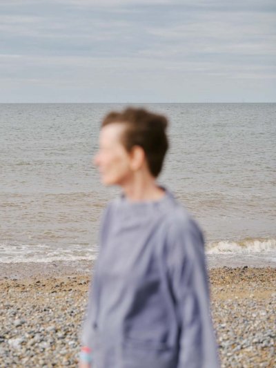 Professor Carol Brayne out of focus pebbles of beach and sea in focus