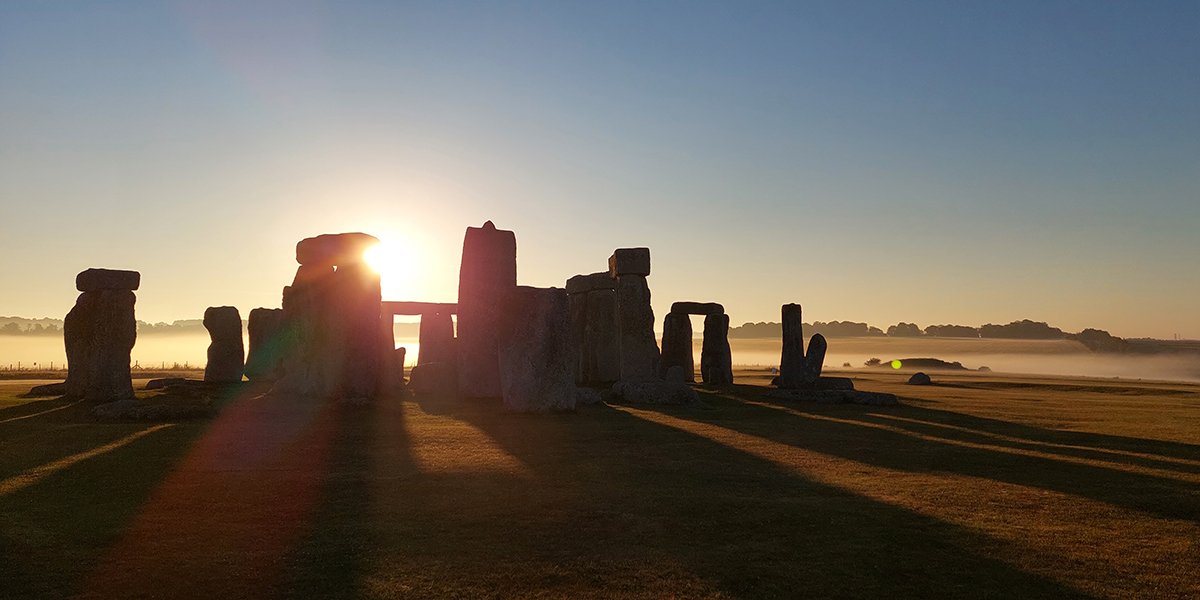 Stone circle at Stonehenge shown with the sun rising from behind the stones