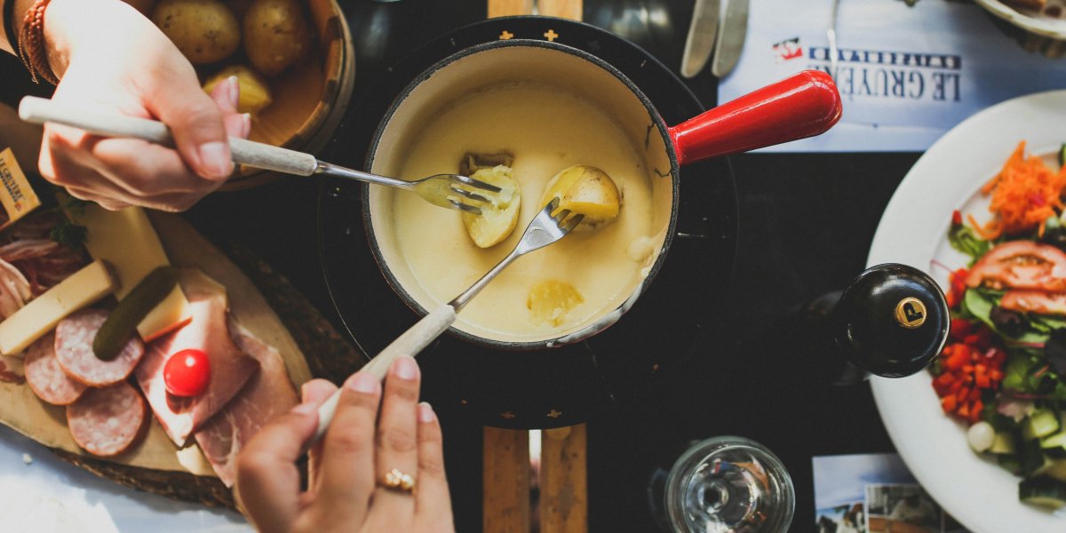 Friends enjoying a classic cheese fondue with potatoes 