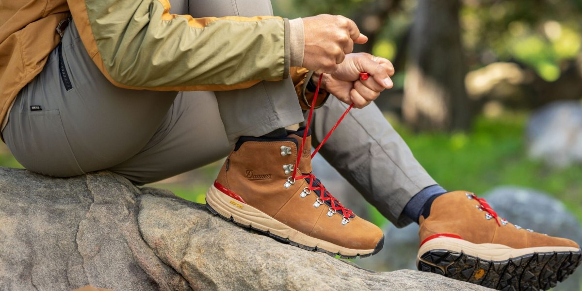 Hiker tying up their hiking boots whilst sat on a rock.